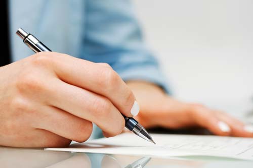 Person signing a document in pen